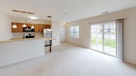 This single-floor residence is designed with a practical, open layout that connects the main living spaces seamlessly. The living area is generously proportioned, finished with neutral-toned wall-to-wall carpeting that extends throughout the bedrooms, and is bathed in natural light through a large sliding glass door that opens to an outdoor view — a standout feature of the space. An additional window in the living area further enhances the brightness of the room.

The kitchen is positioned adjacent to the living area and features a breakfast bar peninsula that serves as a natural divider between the two spaces. Warm medium-toned wood cabinetry lines the walls, complemented by light countertops, a tiled backsplash, and a full suite of stainless steel appliances, including a gas range, built-in microwave, and refrigerator. Light tile flooring anchors the kitchen area.

Multiple bedrooms offer comfortable proportions, each carpeted and equipped with windows that allow natural light and outdoor views. Closet access is present in the bedrooms.

Two bathrooms serve the unit. The full bathroom includes a tub-shower combination, tile flooring, and wood vanity cabinetry. A second bathroom provides additional convenience, featuring tile flooring and a tall wood storage cabinet, offering practical storage solutions.