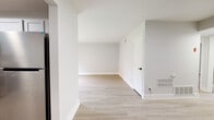 Located at 107 S Comanche Ct in Virginia Beach, Virginia, this single-floor home offers a thoughtfully updated interior with a bright, neutral palette and consistent design choices throughout. The open living areas feature light hardwood-style flooring that flows seamlessly between rooms, creating a cohesive and airy feel. Crisp white walls and white trim complement the clean aesthetic, while multiple doorways and open sightlines contribute to a spacious, connected layout.

The kitchen is a standout feature, showcasing two-tone cabinetry with gray lower cabinets accented by gold hardware and white upper cabinets. Butcher block countertops add warmth, while a matte black sink and stainless steel appliances — including a gas range and over-the-range microwave — provide a modern, functional workspace. A window above the sink allows natural light to fill the space.

The bedrooms offer a mix of flooring, with one featuring plush carpeting and a standard closet with a built-in rod, and another with hardwood-style flooring and a dedicated closet area. The bathroom includes a full tub and shower combination fitted with sleek matte black fixtures against clean white surrounds. The floor plan, visible in the dollhouse view, reveals an efficient and well-organized single-story layout designed for comfortable everyday living.