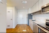This thoughtfully designed studio unit at 141 South Harrison Street in East Orange, NJ offers a clean, modern aesthetic throughout. The open-plan kitchen and living area forms the heart of the space, featuring warm wood-look luxury vinyl plank flooring, recessed lighting, and bright white walls that enhance the sense of openness. The kitchen is well-appointed with stainless steel appliances — including a refrigerator, electric range, built-in microwave, and dishwasher — paired with glossy white upper cabinetry, wood-toned lower cabinets, and a sleek marble-look countertop and backsplash. The living area benefits from a large window that invites natural light and provides views of the surrounding East Orange skyline. A wall-mounted HVAC unit ensures year-round climate control. The bathroom showcases contemporary finishes, including large-format tile flooring, a striking decorative mosaic accent wall, a floating wood-vanity with an illuminated mirror, and a full soaking tub with a tiled surround. Two closets provide practical storage, and dedicated laundry facilities add convenience. The overall ambiance is fresh, modern, and efficiently laid out — ideal for those seeking a functional and stylish urban residence.