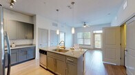 Located at 100 District Dr in Asheville, NC, this well-appointed two-bedroom, two-bathroom residence offers a thoughtfully designed single-floor layout. The open-concept kitchen serves as the centerpiece of the living area, featuring granite countertops, a large center island with undermount sink and pendant lighting, gray shaker-style cabinetry, subway tile backsplash, and a full suite of stainless steel appliances including a French door refrigerator, electric range, microwave, and dishwasher. Track and pendant lighting illuminate the space, which flows seamlessly into the living area, where a ceiling fan and large windows invite abundant natural light. Light-toned hardwood-style flooring runs throughout the home, lending warmth and continuity. The bedrooms are bright and well-sized, with the primary bedroom offering a comfortable footprint complemented by generous closet space. In total, five closets provide exceptional storage throughout the unit, including spacious walk-in closets with wire shelving systems. Both bathrooms are finished with granite vanities, gray-toned tile surrounds, and soaking tub-shower combinations with brushed nickel fixtures. A dedicated laundry area adds everyday convenience. Clean white walls, modern finishes, and a functional layout make this Asheville residence a polished and practical home.