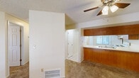 This single-floor, 2-bedroom, 1-bathroom residence offers a practical and comfortable layout designed for efficient everyday living. The living room serves as the central gathering space, featuring warm neutral carpet, a ceiling fan with integrated light, a textured ceiling, and a floor-level air vent for climate control. It connects seamlessly to the kitchen via an open pass-through counter with warm wood cabinetry, making the space feel open and connected.

The kitchen is well-appointed with abundant oak-toned upper and lower cabinetry, light-colored countertops, a double-basin sink, a white electric range, a dishwasher, and a full-size refrigerator. Light tile flooring and a window allowing natural light round out this functional cooking space.

Both bedrooms are carpeted and include ceiling fans with lighting and windows that bring in natural light. Each bedroom is equipped with a sliding-door closet featuring a hanging rod and shelf, providing practical storage solutions.

The unit also includes two hallways and two closets that contribute to overall storage capacity. The neutral color palette throughout — cream walls, beige carpet, and white trim — creates a clean, cohesive aesthetic that is easy to personalize.