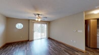 This single-floor space offers a thoughtfully designed layout that balances comfort and functionality. The open-concept living area is finished with rich, dark hardwood-style flooring and features a ceiling fan with light fixture, providing both comfort and warmth. A sliding glass door with vertical blinds fills the space with natural light and offers outdoor views, while a charming circular accent window near the entryway adds architectural interest.

The kitchen is a standout feature, showcasing warm honey-toned wood cabinetry, granite-look countertops, and a mosaic tile backsplash. A full suite of stainless steel appliances — including a refrigerator, range, built-in microwave, and dishwasher — provides everything needed for daily living. Light wood-tone flooring ties the kitchen seamlessly to the adjoining living space.

The bedroom is finished with plush carpeting and benefits from a window that allows natural light to brighten the room. A textured ceiling is consistent throughout the space, adding subtle visual depth.

The bathroom is well-appointed with a granite-topped vanity, wood cabinetry, a large mirror, modern light fixtures, and a tub-shower combination. Hardwood-style flooring continues into the bathroom, maintaining a cohesive aesthetic throughout. The overall ambiance of the space is clean, neutral, and move-in ready.