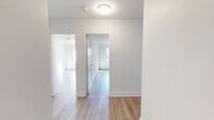 This well-appointed 2-bedroom, 1-bathroom unit offers a clean, modern aesthetic throughout its single-floor layout. Light-toned hardwood flooring flows seamlessly across every room, complemented by crisp white walls and white trim that create a bright, airy atmosphere.

The galley-style kitchen is a functional highlight, featuring white shaker cabinetry, dark countertops, a subway tile backsplash, stainless steel appliances, and a undermount sink — offering a polished and contemporary finish.

The combined living and dining area is generously sized, bathed in natural light, and opens directly onto a private balcony through a large sliding glass door. The balcony overlooks a lush, green landscape with mature trees, providing a pleasant outdoor retreat.

Both bedrooms are well-proportioned, each featuring large windows that invite natural light and offer views of the surrounding greenery. The primary bedroom provides a comfortable and spacious personal retreat.

The bathroom is neatly finished with a full tub-and-shower combination, fully tiled in classic white subway tile with chrome fixtures, complemented by neutral tile flooring. Baseboard heating is present throughout the unit. The hallway connects all rooms efficiently, enhancing the overall flow of the layout.