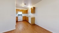 Located at 1501 S Main St in Stillwater, Oklahoma, this single-floor unit offers a practical and efficient layout across a modest footprint. The space is organized into a kitchen, bedroom, bathroom, and dedicated closet, making efficient use of every square foot.

The kitchen is a standout feature, outfitted with warm oak cabinetry extending to the upper and lower walls in an L-shaped configuration. White appliances — including an electric range and dishwasher — pair with a double basin sink beneath a window that allows natural light to filter in. Light wood-look laminate flooring runs throughout the kitchen and bathroom, adding warmth to the space.

The bedroom offers a comfortable, carpeted retreat with a ceiling fan overhead and a window that provides natural light and ventilation. An open closet with built-in shelving provides organized storage, while an additional door connects conveniently to the rest of the unit.

The bathroom continues the oak cabinetry theme with a wood-toned vanity, medicine cabinet, and wall mirror, complemented by a lighted vanity bar. A grab bar installation adds a practical accessibility feature. The light laminate flooring ties the bathroom seamlessly to the rest of the unit's aesthetic.

Overall, this unit presents a clean, neutral palette of white walls and natural wood tones, creating a simple and functional living environment in Stillwater, OK.