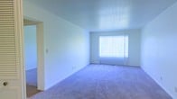 Located at 4992 Richland Dr. in South Charleston, West Virginia, this single-floor residence offers a clean and straightforward layout designed for comfortable everyday living. The interior presents a bright, open living area finished with plush wall-to-wall carpeting that adds warmth and softness underfoot. Crisp white walls throughout the space create a fresh, neutral backdrop that lends itself well to a variety of décor styles. A large window fitted with vertical blinds allows abundant natural light to fill the room, creating an airy and welcoming atmosphere. The smooth, light-toned ceiling complements the overall brightness of the interior. The open layout of the main living area provides a generous sense of space, with clean sightlines and an uncluttered feel. Doorways connect to adjoining rooms, maintaining a logical and accessible flow throughout the home. The combination of neutral finishes, soft flooring, and ample natural light gives the residence a calm, move-in-ready character suitable for a range of occupants.
