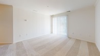 Located at 2000 Varsity Ln in Bear, Delaware, this single-floor residence offers a clean, neutral aesthetic throughout. The spacious living area is finished with plush wall-to-wall carpeting and features a sliding glass door dressed with vertical blinds, allowing natural light to fill the room and providing access to the outdoors. Adjacent to the living space, the entry area includes a double-door closet and an open pass-through view into the kitchen, creating a connected and functional layout. The kitchen is efficiently designed with light wood cabinetry, granite-style laminate countertops, tile flooring, and white appliances including a refrigerator and electric range, complemented by a dishwasher. The bedrooms continue the warm, carpeted theme — one features a ceiling fan and a window with blinds, while another offers a similarly bright and open feel with its own window. Both rooms provide a comfortable, versatile space. The bathroom is well-appointed with a full soaking tub and shower combination, chrome fixtures, tile flooring, and a vanity with a white countertop. Throughout the residence, the consistent use of light tones, clean lines, and neutral finishes creates a cohesive and welcoming atmosphere.