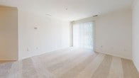 Located at 2000 Varsity Ln in Bear, Delaware, this single-floor residence offers a clean, neutral aesthetic throughout. The spacious living area is finished with plush wall-to-wall carpeting and features a sliding glass door dressed with vertical blinds, allowing natural light to fill the room and providing access to the outdoors. Adjacent to the living space, the entry area includes a double-door closet and an open pass-through view into the kitchen, creating a connected and functional layout. The kitchen is efficiently designed with light wood cabinetry, granite-style laminate countertops, tile flooring, and white appliances including a refrigerator and electric range, complemented by a dishwasher. The bedrooms continue the warm, carpeted theme — one features a ceiling fan and a window with blinds, while another offers a similarly bright and open feel with its own window. Both rooms provide a comfortable, versatile space. The bathroom is well-appointed with a full soaking tub and shower combination, chrome fixtures, tile flooring, and a vanity with a white countertop. Throughout the residence, the consistent use of light tones, clean lines, and neutral finishes creates a cohesive and welcoming atmosphere.