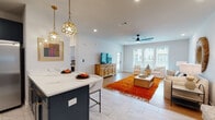 Located at 270 Tallassee Rd in Athens, GA, this single-floor home offers a thoughtfully designed open-concept layout that seamlessly blends the kitchen, dining, and living areas. The kitchen is a standout feature, boasting navy blue shaker-style cabinetry with gold hardware, quartz countertops, a classic white subway tile backsplash, and stainless steel appliances. A navy island with bar seating and a pair of decorative gold pendant lights adds both function and style. Marble-look tile flooring anchors the kitchen and dining space, transitioning into warm hardwood in the living area. The living room is bright and welcoming, featuring large windows that allow generous natural light, a modern ceiling fan, and an open door leading outside. The bedroom is a serene retreat with hardwood floors, ample natural light, a ceiling fan, and access to a spacious walk-in closet with wire shelving. The bathroom continues the home's cohesive aesthetic with navy cabinetry, quartz countertops, marble-look tile flooring, a subway-tiled tub surround, and stylish boho-inspired décor accents. Throughout the home, clean white walls and recessed lighting create a bright, modern ambiance.