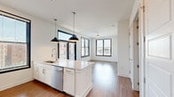 Located at 601 Indian St in the heart of Savannah, Georgia, this modern one-bedroom, one-bathroom unit offers a thoughtfully designed open-concept layout with clean finishes throughout. Wide-plank hardwood-style flooring flows seamlessly across the entire space, complementing the crisp white walls and creating a bright, cohesive aesthetic.

The combined kitchen and living area serves as the centerpiece of the unit. The kitchen features a large island with quartz countertops, white shaker cabinetry, a stainless steel refrigerator with ice maker, a stainless steel range, microwave, and dishwasher. Dual black pendant lights hang above the island, adding a contemporary touch. Black-framed windows allow generous natural light and offer views of the surrounding Savannah cityscape.

The bedroom is a comfortable, well-proportioned retreat with two large black-framed windows that frame urban views. A ceiling fan provides added comfort, and a dedicated closet offers practical storage.

The full bathroom is finished with a white tile tub-shower combination, a quartz-topped vanity with white cabinetry, and hardwood-style flooring. Additional utility is provided through a dedicated laundry area and a separate utility room. The overall ambiance is clean, modern, and move-in ready.