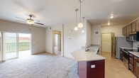 Located at 1803 Moon Meadows Dr in Rapid City, South Dakota, this two-bedroom, one-bathroom unit offers a well-designed single-level layout with a comfortable footprint. The open-concept living and dining area features plush carpeting and a ceiling fan, creating a relaxed, airy atmosphere. Sliding glass doors lead to a private balcony with an open railing, offering unobstructed views of the surrounding grasslands and distant hills.

The kitchen is well-appointed with rich dark cabinetry, granite countertops, a subway tile backsplash, and stainless steel appliances including a refrigerator, range, and built-in microwave. A peninsula with pendant lighting and an integrated sink connects the kitchen to the main living space.

Both bedrooms are carpeted and equipped with ceiling fans. The primary bedroom includes a walk-in closet featuring wire shelving for organized storage. The second bedroom offers a window with pleasant outdoor views. The full bathroom features a granite-topped vanity with dark wood cabinetry, a tub-shower combination with decorative tile accenting, and tile flooring. The overall aesthetic is clean and consistent throughout.