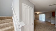 Located at 437 Sunburst Dr in Delaware, Ohio, this two-story home offers a practical and comfortable layout spread across two floors. The main level features a carpeted living room filled with natural light from a sliding glass door fitted with vertical blinds, alongside a well-equipped kitchen. The kitchen includes warm-toned wood cabinetry with ample storage, granite-style countertops, a double-basin sink beneath a window, and a full suite of black appliances including a refrigerator, range, over-the-range microwave, and dishwasher, all set on light hardwood-style flooring. The upper floor houses both bedrooms, each featuring neutral carpet, soft gray walls, and windows with blinds that allow natural light. The second bedroom includes a closet with built-in shelving. The spacious primary bedroom comes with its own en-suite bathroom, which features a double-sink vanity with warm wood cabinetry and granite-style countertops, a stand-up glass-enclosed shower, tile flooring, and a window for natural ventilation. Two additional bathrooms serve the home, each finished with consistent vanity styling. Hallways on both floors provide smooth transitions between spaces, with a carpeted staircase connecting the two levels.