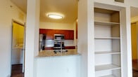This single-floor unit offers a thoughtfully designed open layout that connects the main living areas seamlessly. The spacious living room is finished with plush carpeting, crown molding, and a ceiling fan, and receives generous natural light through multiple windows fitted with blinds. A sliding glass door opens directly onto a private balcony, extending the living space outdoors with views of the surrounding area. Hardwood-style flooring transitions the space from the living room into the kitchen and entryway areas.

The kitchen is outfitted with rich, warm-toned cabinetry, granite-style countertops, and a classic white subway tile backsplash. A peninsula with a built-in sink and matching countertop serves as both a functional workspace and a natural divider between the kitchen and living areas. Stainless steel appliances — including a refrigerator, microwave, and range — as well as a dishwasher, complete the kitchen. A pantry or utility door provides additional storage access within the kitchen.

The bedroom is a quiet, carpeted retreat featuring a bright window with blinds. The bathroom includes warm wood-toned cabinetry, a stone-finish vanity countertop, an undermount sink with brushed nickel fixtures, and a large mirror. Built-in shelving is also present, offering practical storage throughout the unit.
