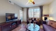 This thoughtfully designed single-floor residence offers a functional and stylish layout across a comfortable footprint. The living room serves as the heart of the home, featuring wood-style flooring, a ceiling fan, and a large window dressed with vertical blinds and draping curtains that flood the space with natural light. A private exterior door provides added convenience directly from the living area. Adjacent to the living room, the dedicated dining space is framed by neutral walls and accented with decorative wall art, creating an intimate setting. The kitchen is well-equipped with light wood cabinetry, granite-style countertops, stainless steel appliances including a refrigerator, electric range, and built-in microwave, offering ample storage and prep space. The spacious primary bedroom features plush carpeting, a ceiling fan, a large window with outdoor views, a neutral accent wall, and direct access to a walk-in closet. The bathroom includes a full soaking tub and shower combination with tile surround and wood-style flooring. Throughout the home, consistent wood-style flooring, neutral tones, and thoughtful design details create a cohesive and inviting ambiance.