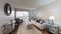 This single-story residence at 835 West Avenue L offers a thoughtfully arranged floor plan that connects key living areas in a cohesive, functional layout. The kitchen is outfitted with white cabinetry, a double-basin sink, a built-in dishwasher, and a notable skylight that draws natural light directly into the workspace. Warm wood-look flooring runs throughout the kitchen and extends into adjacent areas, lending a consistent visual flow.

The living room is a welcoming, open space anchored by large sliding glass doors fitted with vertical blinds, allowing for generous natural light and outdoor views onto what appears to be a balcony or patio. Wood flooring continues here, complementing the neutral wall tones and textured ceiling throughout.

The bedrooms feature plush carpeting and windows with vertical blinds that provide privacy while allowing light. Each room offers a calm, neutral palette and practical dimensions suitable for standard bedroom furnishings. One bedroom benefits from closet access and appears to connect to a shared or en-suite bathroom. That bathroom is equipped with a dual-sink vanity topped with neutral countertops, white cabinetry, well-lit mirrors, and a separate enclosed shower, making it both functional and organized.