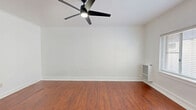 Located at 687 Shatto Place in the heart of Los Angeles, CA, this efficiently designed single-floor unit offers a well-organized layout comprising a living room, kitchen, bathroom, closet, and hallway. Rich wood-look flooring runs consistently throughout the space, complemented by crisp white walls and clean white baseboards that create a bright, cohesive aesthetic.

The living room serves as the central gathering area, featuring a ceiling fan with integrated lighting and a large window dressed with horizontal blinds that allows natural light to fill the room. A wall-mounted heater unit provides climate control.

The kitchen is thoughtfully appointed with white cabinetry featuring decorative raised-panel doors and brushed nickel hardware. A double-basin stainless steel sink sits beneath upper cabinets, while a gas range with a stainless steel finish and a countertop microwave complete the functional cooking setup. Granite-look countertops tie the space together.

The hallway connects the main living areas to the bathroom, which offers a full bathtub-shower combination with white subway tile surround and a window for natural ventilation. White doors with brushed nickel hardware maintain a consistent design language throughout. A dedicated closet provides practical storage, maximizing the utility of this compact yet well-appointed Los Angeles residence.