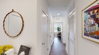 This thoughtfully designed single-floor residence offers a seamless blend of modern aesthetics and functional living. The open-concept living and dining area serves as the heart of the home, featuring rich hardwood-style flooring, recessed lighting, and large windows alongside sliding glass doors that lead to a private balcony — flooding the space with natural light and offering views of the surrounding urban streetscape.

The kitchen is a standout feature, outfitted with flat-front light wood cabinetry, dark quartz countertops, a classic subway tile backsplash, and a full suite of stainless steel appliances. A central island provides additional prep and casual dining space, completing this highly functional culinary environment.

A well-proportioned hallway connects the private quarters of the residence, lined with closet storage and leading to two distinct bedrooms. The primary bedroom features a striking textured accent wall, warm wood flooring, and a large window that invites in natural light. The second bedroom is bright and airy, with an oversized window framing exterior views. The bathroom is cleanly finished with light tile flooring, a dark wood vanity, and a walk-in shower, maintaining the home's consistent modern sensibility throughout.