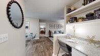 This single-floor residence offers a thoughtfully designed open-concept layout that seamlessly connects the living, dining, and kitchen areas. The living room is a welcoming space highlighted by wood-style flooring, a ceiling fan, and large windows that invite abundant natural light. A glass-top coffee table and tasteful wall art complete the area's refined aesthetic. The adjacent dining space accommodates a small table and chairs, while an integrated breakfast bar with granite countertops and built-in shelving provides additional seating and storage.

The kitchen is well-equipped with white cabinetry, granite countertops, black appliances including a refrigerator, electric range, and dishwasher, along with a double sink and wood-style flooring for easy maintenance.

The unit features two carpeted bedrooms, each offering a comfortable and serene retreat. Both rooms are generously sized with large windows dressed in blinds and sheer curtains, allowing for natural light while maintaining privacy. The primary bedroom connects to a full bathroom complete with granite-topped white vanity cabinetry, a tub-shower combination, and wood-style flooring. A second full bathroom mirrors this design, offering equal functionality and style throughout the home.