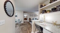 This single-floor residence offers a thoughtfully designed open-concept layout that seamlessly connects the living, dining, and kitchen areas. The living room is a welcoming space highlighted by wood-style flooring, a ceiling fan, and large windows that invite abundant natural light. A glass-top coffee table and tasteful wall art complete the area's refined aesthetic. The adjacent dining space accommodates a small table and chairs, while an integrated breakfast bar with granite countertops and built-in shelving provides additional seating and storage.

The kitchen is well-equipped with white cabinetry, granite countertops, black appliances including a refrigerator, electric range, and dishwasher, along with a double sink and wood-style flooring for easy maintenance.

The unit features two carpeted bedrooms, each offering a comfortable and serene retreat. Both rooms are generously sized with large windows dressed in blinds and sheer curtains, allowing for natural light while maintaining privacy. The primary bedroom connects to a full bathroom complete with granite-topped white vanity cabinetry, a tub-shower combination, and wood-style flooring. A second full bathroom mirrors this design, offering equal functionality and style throughout the home.