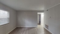 Located on Shawnee Dr in Burlington, NC, this single-floor home presents a clean, updated interior with a cohesive neutral color palette and consistent luxury vinyl plank flooring carried throughout every room. The living area is open and well-proportioned, featuring smooth walls painted in soft gray tones, clean white trim and baseboards, and a built-in shelving unit that adds functional character. A large window allows natural light to fill the space, contributing to a bright and airy atmosphere. The kitchen is outfitted with white shaker-style cabinetry, granite-look countertops, a stainless steel sink, and a dishwasher. A window positioned above the sink and a door providing exterior access allow additional natural light into the space. The bedrooms are comfortably sized and each features sliding-panel closets with built-in rods and shelving for organized storage. The bathroom includes a full tub and shower combination with a white surround, chrome fixtures, and a curved shower rod. Throughout the home, the design is consistent and practical, with smooth ceilings, well-maintained walls, and updated finishes that give the space a fresh, move-in-ready appearance.