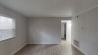 Located on Shawnee Dr in Burlington, NC, this single-floor home presents a clean, updated interior with a cohesive neutral color palette and consistent luxury vinyl plank flooring carried throughout every room. The living area is open and well-proportioned, featuring smooth walls painted in soft gray tones, clean white trim and baseboards, and a built-in shelving unit that adds functional character. A large window allows natural light to fill the space, contributing to a bright and airy atmosphere. The kitchen is outfitted with white shaker-style cabinetry, granite-look countertops, a stainless steel sink, and a dishwasher. A window positioned above the sink and a door providing exterior access allow additional natural light into the space. The bedrooms are comfortably sized and each features sliding-panel closets with built-in rods and shelving for organized storage. The bathroom includes a full tub and shower combination with a white surround, chrome fixtures, and a curved shower rod. Throughout the home, the design is consistent and practical, with smooth ceilings, well-maintained walls, and updated finishes that give the space a fresh, move-in-ready appearance.