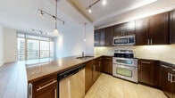 Located in the heart of downtown Austin at 101 Colorado St, this one-bedroom, one-bathroom high-rise unit offers a thoughtfully designed open-concept layout. The combined dining, kitchen, and living area forms the centerpiece of the home, finished with tile flooring that transitions seamlessly into wood-look plank floors throughout the living spaces. The kitchen is well-appointed with rich dark espresso cabinetry, granite countertops, a large peninsula with a built-in wine rack, stainless steel appliances including a double oven, microwave, refrigerator, and dishwasher, complemented by tile backsplash and pendant and track lighting. Floor-to-ceiling sliding glass doors in the living area open to a private balcony, flooding the space with natural light and offering elevated views of the Austin skyline. The spacious bedroom features a ceiling fan, large windows with striking city views, and access to a generous walk-in closet with wire shelving. The bathroom is finished with travertine tile, a soaking tub/shower combo, dark wood vanity cabinetry, and an adjacent closet. Additional conveniences include a dedicated laundry area, utility room, and hallway storage.