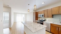 Located in Leawood, Kansas, this well-appointed 1-bedroom, 1-bathroom residence offers a thoughtfully designed open-concept layout. The kitchen serves as a central highlight, featuring rich warm-toned wood cabinetry, a full suite of stainless steel appliances, a glass tile backsplash, and an expansive granite-topped island with pendant lighting overhead — ideal for both meal prep and casual dining. Light wood-style flooring flows throughout the main living areas, enhancing the bright, airy atmosphere created by recessed lighting and large windows.

The living room is generously sized, bathed in natural light from a sliding glass door that opens to a private balcony overlooking a green outdoor landscape. The bedroom offers plush carpeting, a ceiling fan, and a dedicated window with blinds for natural light and privacy. A walk-in closet provides practical storage. The bathroom is finished with large-format tile flooring, a tiled soaking tub surround, and a wood-cabinet vanity with granite countertop, maintaining the cohesive design language found throughout the space. Clean white walls and neutral tones lend a modern, move-in-ready aesthetic throughout the entire residence.