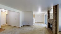 This single-floor residence offers a clean, functional layout designed for comfortable everyday living. The open living and dining area is finished with wall-to-wall carpeting that extends throughout, providing a warm and cohesive feel underfoot. Crisp white walls and a textured ceiling keep the interiors bright and neutral, offering a versatile backdrop for a variety of décor styles.

A pendant light fixture hangs above the dining area, adding a subtle focal point to the space. A baseboard heating unit runs along the exterior wall, ensuring efficient climate control throughout the colder months. Sliding glass doors in the dining area allow natural light to filter in and provide a connection to the outdoors.

The layout includes a partitioned area that creates a sense of separation between the living and dining zones without fully closing off the space, maintaining an airy, open atmosphere. A sliding closet door is visible along one wall, offering convenient built-in storage.

Adjacent to the dining area, a glimpse of warm-toned cabinetry hints at a connected kitchen, rounding out the practical and straightforward design of this well-maintained single-floor home.