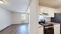 Located at 7 Squire Lane in East Providence, Rhode Island, this one-bedroom, one-bathroom residence offers a practical and well-organized single-floor layout. The living area features hardwood-style flooring that reflects natural light from a window overlooking greenery, creating a bright and welcoming atmosphere. A wall-mounted HVAC unit provides climate control directly in the living space.

The galley-style kitchen is efficiently designed with white shaker cabinetry lining both sides, stone-look countertops, and stainless steel appliances including a refrigerator, electric range, and dishwasher. Light wood flooring and under-cabinet lighting enhance functionality and visual appeal.

The bedroom offers plush carpeting, a natural light source through a window, a wall-mounted baseboard heater, and a dedicated closet with sliding panel doors and a full-length hanging rod. An additional hallway closet provides supplementary storage.

The bathroom is clean and straightforward, featuring a full tub-shower combo with bright white surround, wood-style flooring, a vanity with sink, and safety grab bars. A hallway connects the main areas of the unit, contributing to a logical and easy-to-navigate floor plan. Overall, the space delivers a functional, no-frills living environment with essential amenities in a residential East Providence neighborhood.