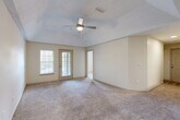 This well-appointed three-bedroom, two-bathroom home in Villa Rica, Georgia offers a thoughtfully designed single-floor layout. The spacious living room is a standout feature, boasting vaulted ceilings with a ceiling fan and light kit, neutral carpet flooring, and a glass door that invites natural light and outdoor access. The open-concept kitchen flows seamlessly into the living area and features a peninsula with a built-in sink, light-toned cabinetry, a stainless steel refrigerator, and light wood-look flooring beneath, complemented by overhead lighting. A hallway connects the main living spaces to the three bedrooms, each carpeted and filled with natural light from blinded windows. The spacious primary bedroom includes a vaulted ceiling with a ceiling fan, providing a comfortable and airy retreat. Two full bathrooms serve the home, including one with a tiled tub-shower combination, a vanity with light countertops, and wood-look flooring. A dedicated laundry room houses a full-size washer and dryer with overhead shelving and light wood-look flooring. Four closets throughout the home provide ample storage. The overall aesthetic is clean, bright, and neutral, creating a welcoming and versatile living environment.
