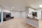 Located at 14274 SE 6th St in Bellevue, WA, this thoughtfully updated 2-bedroom, 2-bathroom residence offers a well-designed single-floor layout that maximizes every square foot. Light-toned hardwood-style flooring flows seamlessly throughout, lending a clean, cohesive aesthetic to the entire space.

The open-concept living area is anchored by a modern tile-surround fireplace and is bathed in natural light, with recessed lighting overhead for added warmth in the evenings. The kitchen is a functional highlight, featuring crisp white shaker cabinetry, quartz countertops, a tile backsplash, stainless steel appliances including a refrigerator, range, microwave, and dishwasher, and a peninsula that opens to the living space. A stacked washer and dryer unit is conveniently tucked within the layout.

Both bedrooms are well-proportioned and finished with neutral tones and large windows that invite natural light and views of the surrounding lush greenery. The primary bedroom benefits from sliding glass doors that open directly to an outdoor deck surrounded by verdant foliage. Each bathroom is cleanly appointed with white tub-shower combinations, undermount sinks, and matte black fixtures that add a contemporary touch. A hallway connects the rooms, keeping the layout efficient and accessible.