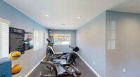 Located at 404 Jones Ferry Rd in Carrboro, NC, this dedicated exercise room offers a complete fitness environment within a compact, efficiently utilized single-floor layout. The space is finished with cool blue-gray walls, white baseboards, and dark flooring that lends a clean, professional aesthetic throughout.

Recessed lighting is evenly distributed across the ceiling, ensuring the room is well-lit at all times, while multiple windows fitted with white blinds allow for natural light and ventilation. A ceiling-mounted HVAC vent supports comfortable climate control during workouts.

The room is thoughtfully organized to accommodate a variety of fitness activities. Cardio equipment includes a treadmill and a rowing machine, while strength training needs are addressed by a multi-function cable machine and a tiered dumbbell rack stocked with a full range of free weights. A flat workout bench rounds out the strength training area. On the functional fitness side, the space features an assortment of stability and medicine balls displayed on a dedicated rack.

A wall-mounted paper towel dispenser and hand sanitizer station reflect a commitment to hygiene and user convenience. An exit door with a safety sign provides direct outdoor access. The overall ambiance is focused and functional, making this exercise room a practical and well-appointed fitness facility.