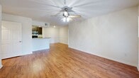 Located in Tampa, FL, this single-floor, one-bedroom, one-bathroom residence offers a well-organized layout designed for comfortable everyday living. The open living area greets you with warm hardwood-style flooring, crisp white walls, and a ceiling fan with integrated lighting. French doors along one wall invite natural light and provide a view of the surrounding greenery, enhancing the bright, airy feel of the space. The kitchen and living room share an open-concept arrangement, with the kitchen featuring a peninsula counter topped with granite, dark espresso cabinetry, stainless steel appliances including a microwave and refrigerator, and a black range. This setup creates a functional and visually connected cooking and gathering area. A hallway leads to the private bedroom, which is carpeted for comfort and includes its own ceiling fan, a window with natural light, and ample wall space. A dedicated closet provides convenient storage. The bathroom is clean and well-appointed, offering a full tub-shower combination with tile surround, brushed nickel fixtures, a granite-topped vanity with dark cabinetry, and hardwood-style flooring. A laundry area rounds out the home's practical amenities, making this a complete and efficient living space.