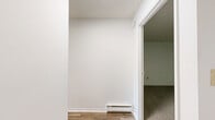 Located at 392 State St in North Haven, Connecticut, this one-bedroom, one-bathroom residence offers a well-organized single-floor layout that makes efficient use of its space. The interior is finished with clean white walls throughout, creating a bright and neutral backdrop across all rooms.

The living area features smooth hardwood-style flooring that reflects natural light, lending an open and airy feel to the space. Built-in shelving adds a practical storage element along one wall. The layout flows naturally into the kitchen, which is equipped with warm oak cabinetry, white laminate countertops, a stainless steel sink, and a full suite of white appliances including a refrigerator, dishwasher, and range.

The generously sized bedroom is one of the standout features of this residence, offering a wall of large windows that flood the room with natural light and provide views of the surrounding greenery. The bedroom also includes a wall-unit air conditioner and baseboard heating for year-round comfort.

The full bathroom is finished with classic white tile surrounding a tub-shower combination, complemented by a white vanity with cabinet storage and a round mirror. The carpeted areas in the bedroom add a layer of warmth and comfort. Overall, the space presents a clean, functional, and well-lit living environment.