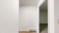 Located at 392 State St in North Haven, Connecticut, this one-bedroom, one-bathroom residence offers a well-organized single-floor layout that makes efficient use of its space. The interior is finished with clean white walls throughout, creating a bright and neutral backdrop across all rooms.

The living area features smooth hardwood-style flooring that reflects natural light, lending an open and airy feel to the space. Built-in shelving adds a practical storage element along one wall. The layout flows naturally into the kitchen, which is equipped with warm oak cabinetry, white laminate countertops, a stainless steel sink, and a full suite of white appliances including a refrigerator, dishwasher, and range.

The generously sized bedroom is one of the standout features of this residence, offering a wall of large windows that flood the room with natural light and provide views of the surrounding greenery. The bedroom also includes a wall-unit air conditioner and baseboard heating for year-round comfort.

The full bathroom is finished with classic white tile surrounding a tub-shower combination, complemented by a white vanity with cabinet storage and a round mirror. The carpeted areas in the bedroom add a layer of warmth and comfort. Overall, the space presents a clean, functional, and well-lit living environment.