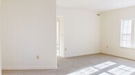 This single-floor unit offers a surprisingly functional layout across four bedrooms, one full bathroom, a kitchen, and a dedicated closet. The living areas are finished with neutral-toned carpet throughout, and multiple windows with blinds invite generous natural light, casting bright patterns across the floors and creating an open, airy atmosphere despite the compact footprint.

The spacious primary bedroom stands out as the largest room in the unit, offering ample space and access to a walk-in closet equipped with wire shelving for organized storage. The additional bedrooms are well-proportioned with carpeted floors and bright windows, one of which features a glass-paned exterior door providing direct outdoor access and added natural light.

The galley-style kitchen is efficiently designed with light wood cabinetry, dark laminate countertops, a stainless steel refrigerator and oven range, a built-in dishwasher, and a central window fitted with blinds. Light tile flooring completes the clean, functional aesthetic.

The full bathroom includes a shower-tub combination, a vanity, and a window with blinds that provides natural ventilation. Throughout the unit, crisp white walls, clean white trim, and consistent neutral tones create a bright, move-in ready environment suited for practical everyday living.