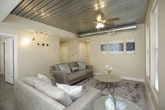 This single-floor unit showcases an urban-inspired aesthetic highlighted by a striking corrugated metal ceiling that runs throughout the main living areas and bedrooms, lending an industrial yet refined character to the space. Exposed ductwork and ceiling fans complement the design, adding both functionality and visual interest.

The open-concept living area is bright and inviting, with multiple windows dressed in white blinds that allow generous natural light to fill the room. The space flows seamlessly into the kitchen, which features white cabinetry, dark granite countertops, stainless steel appliances, a center island with pendant lighting, and polished tile flooring — a well-equipped area ideal for everyday living.

Multiple bedrooms offer a comfortable retreat, each featuring the signature metal ceiling, ceiling fans, carpeted flooring, and ample natural light from large windows. One bedroom includes a walk-in closet, while others provide generous storage options.

The bathrooms are thoughtfully finished with dark granite vanity countertops, white cabinetry, and clean fixtures. The primary bathroom includes a glass-enclosed shower and an elongated layout, while a secondary bathroom offers a compact, functional design with an elegantly lit vanity mirror. Throughout the unit, neutral wall tones and consistent finishes create a cohesive and modern living environment.