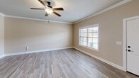 This contemporary single-story residence offers 1050 square feet of well-designed living space. The home features two bedrooms, including a primary bedroom of 170 square feet, and two full bathrooms. The open floor plan promotes a seamless flow between living areas, enhancing the sense of spaciousness.

The kitchen is a standout feature, boasting rich wood cabinetry, sleek black countertops, and stainless steel appliances. The wood-look tile flooring in the kitchen and bathrooms adds warmth and durability. Large windows in the bedrooms and living areas flood the space with natural light, while white trim and crown molding provide elegant finishing touches.

Both bedrooms are generously sized, with the primary bedroom offering ample space for a king-size bed and additional furniture. The bathrooms feature modern vanities with ample storage. Closet space is plentiful throughout, with wire shelving systems for optimal organization.

The neutral color palette, combining soft beige walls with white accents, creates a calming atmosphere and provides a versatile backdrop for various decorating styles. Ceiling fans in the bedrooms offer additional comfort and air circulation.

Located in Huntsville, AL, this home combines modern amenities with practical design, making it an ideal choice for those seeking a contemporary living space in a desirable location.