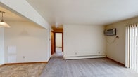 Located on Maryland Court NE in Grand Rapids, Michigan, this two-bedroom, one-bathroom unit offers a straightforward and functional single-floor layout. The living room is a comfortable, open space featuring neutral-toned carpet, baseboard heating, a wall-mounted air conditioning unit, and a sliding glass door that invites natural light and provides views of the surrounding outdoor area. The galley-style kitchen is well-appointed with rich wood cabinetry lining both walls, ample counter space, a double sink, and tile flooring, offering an efficient and organized workspace. The primary bedroom is a generously sized room with carpeted floors, a baseboard heater, and a window that brings in natural light. The second bedroom also features carpet, a window with outdoor views, a baseboard heater, and a closet with built-in shelving and a hanging rod for convenient storage. The bathroom is clean and functional, featuring a combined tub and shower unit with grab bar support, tile flooring, and a built-in shelving unit. Warm wood-toned doors and trim are consistent throughout the unit, providing a cohesive and practical aesthetic across all rooms.