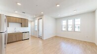 Located on Westwind Street in Livermore, CA, this well-designed one-bedroom, one-bathroom unit offers a clean, modern aesthetic across a single floor. The open-concept kitchen and living area serves as the heart of the home, featuring light wood-tone laminate flooring, recessed lighting, and multiple windows that invite generous amounts of natural light. The kitchen is outfitted with warm wood-grain cabinetry, stainless steel appliances including a refrigerator, electric range, over-the-range microwave, and dishwasher, along with a light-colored countertop and a single-basin sink. The living area provides a bright, open feel with a private entry door and additional windows overlooking the surrounding community. The bedroom is a comfortable, well-proportioned space with soft carpeting, large windows offering neighborhood views, and ample wall space. A dedicated closet provides additional storage. The bathroom features a full tub-shower combo with built-in shelving, a wood-tone vanity, and light wood flooring, maintaining the cohesive modern design found throughout. A hallway connects the rooms efficiently, completing this thoughtfully laid-out and move-in-ready residence.