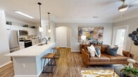 Located at 1800 South Egret Bay Boulevard in League City, TX, this thoughtfully designed one-bedroom, one-bathroom residence offers a well-appointed single-floor layout. Wood-style flooring and crown molding run throughout, creating a cohesive and polished aesthetic.

The open-concept living, dining, and kitchen area serves as the heart of the home. The kitchen features crisp white cabinetry, light countertops, stainless steel appliances including a range, microwave, and refrigerator, and a breakfast bar with pendant lighting — ideal for casual dining or entertaining. The adjoining dining area flows seamlessly into the bright living room, which is framed by large windows that invite natural light and offers direct access to an exterior door.

The bedroom is a comfortable retreat, highlighted by a bold accent wall, ceiling fan, natural light from a dedicated window, and direct access to a spacious walk-in closet. The full bathroom provides a generous vanity with ample counter space, a tub-shower combination, and wood-style flooring for a consistent design feel. An in-unit laundry area and four closets offer excellent storage throughout. The arched interior doorway adds a charming architectural detail that enhances the overall character of the space.