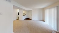 This single-floor residence offers a thoughtfully designed layout that balances comfort and functionality. The spacious living area is finished with plush wall-to-wall carpeting and crisp white walls, creating a bright, clean atmosphere. A pass-through opening connects the living space directly to the kitchen, promoting an open and airy feel throughout.

The kitchen is well-equipped with white shaker-style cabinetry, dark countertops, a double stainless steel sink, a dishwasher, and a stainless steel refrigerator and range. The layout is efficient and practical, with ample counter and storage space. A large sliding glass door in the adjacent area allows natural light to flood the common spaces.

The bedrooms are carpeted and finished with neutral tones, offering a calm and restful environment. Windows dressed with horizontal blinds provide natural light while maintaining privacy. One bedroom features dual windows and direct access to a dedicated walk-in closet, adding a notable storage advantage.

The bathroom includes a full-size tub and shower combination with chrome fixtures, a toilet, and a vanity with a large mirror and speckled countertop. The overall design of the space is clean and understated, with consistent light-toned finishes throughout that lend a welcoming and move-in-ready quality to the home.