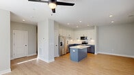 Located at 3801 Apple Way, Unit F in Greenville, NC, this well-appointed two-story home offers 3 bedrooms and 3 full bathrooms across two thoughtfully designed floors. The main level features an open-concept living, dining, and kitchen area filled with natural light from large windows overlooking the covered rear patio. The kitchen is a standout, showcasing two-tone cabinetry — crisp white upper shaker cabinets paired with slate-blue lower cabinets — complemented by a white subway tile backsplash, quartz countertops, stainless steel appliances, and a central island ideal for dining or meal prep. Light wood-look flooring and ceiling fans flow throughout the main living areas, creating a bright, cohesive aesthetic. An attached garage with a window provides convenient single-level access. Upstairs, the generously sized primary bedroom includes an expansive walk-in closet with wire shelving systems, echoed by additional closets across all bedrooms. A dedicated laundry room with a full-size washer and dryer adds everyday convenience. The bathrooms feature clean, modern finishes, including a walk-in shower with floor-to-ceiling white tile and matte black framing. A covered back patio extends the living space outdoors, overlooking a grassy yard.