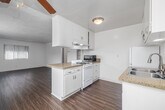Located in Redondo Beach, CA, this well-appointed one-bedroom, one-bathroom unit offers a functional and comfortable single-floor layout. The open-concept living and kitchen area serves as the heart of the home, featuring warm wood-style flooring that flows throughout the main living spaces. The kitchen is equipped with white cabinetry, granite-style countertops, a gas range, a double-basin stainless steel sink, and a full-size refrigerator — providing ample storage and workspace. A peninsula counter connects the kitchen to the living area, enhancing the open feel of the space. Large windows fitted with vertical blinds invite generous natural light into the living room, creating a bright and airy atmosphere. The bedroom is a comfortable retreat with plush carpeting, a ceiling fan with light fixture, and a large window offering outdoor views. Two closets provide convenient storage throughout the unit. The bathroom features a full tub and shower combination with tile surround, a vanity with storage, and a window for natural ventilation. A hallway connects the main living areas to the bedroom and bathroom, completing the efficient and practical floor plan.