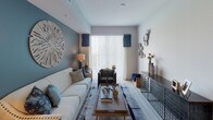 This single-floor residence offers a thoughtfully designed layout that balances modern style with everyday functionality. The kitchen is a standout feature, showcasing dark wood-grain cabinetry, granite countertops, a classic subway tile backsplash, and a full suite of stainless steel appliances including a French door refrigerator, electric range, and built-in microwave. A center island with pendant lighting provides additional prep space and casual dining. Light wood-style flooring flows through the kitchen and into the open living area, which is bathed in natural light from large sliding glass doors. A soothing blue accent wall anchors the living room, creating a calm and welcoming atmosphere. The bedroom is a tranquil retreat, featuring plush carpeting, a soft blue accent wall, and a large arched decorative mirror that adds architectural character. A generously sized walk-in closet offers custom-built shelving, multiple hanging rods, and drawer storage for excellent organization. The bathroom is finished with sleek dark vanity cabinetry, granite countertops, white tile flooring, and a tub-shower combination. Clean lines, neutral tones, and cohesive design details give this residence a polished and comfortable feel throughout.