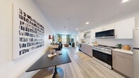 Located at 1100 D St in Las Vegas, NV, this thoughtfully designed one-bedroom, one-bathroom unit makes excellent use of its compact footprint. The open-concept kitchen and living area anchors the space, featuring light wood-style flooring, recessed lighting, and a clean, contemporary aesthetic throughout. The kitchen is well-appointed with stainless steel appliances — including a gas range, built-in microwave, refrigerator, and dishwasher — paired with two-tone cabinetry in white and warm taupe, and a bright white countertop. Natural light fills the living area through a large window dressed with sage green linen curtains, creating a calm, inviting atmosphere. The bedroom offers a comfortable and private retreat, complete with a window overlooking the neighborhood, wood-toned flooring, and a distinctive frosted-glass sliding barn door that connects to the bathroom. The bathroom features sleek white cabinetry, an integrated sink with modern fixtures, and a full-height storage tower. A stacked in-unit washer and dryer is conveniently integrated into the hallway. The unit's neutral palette, modern hardware, and cohesive design elements make it a functional and stylish home in the heart of Las Vegas.