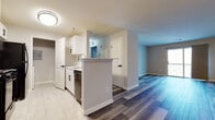 This single-floor residence in Lawrence Township, New Jersey, presents a clean, contemporary design with thoughtfully selected finishes throughout. The open-concept layout connects the kitchen and living areas seamlessly, creating an efficient and functional flow. Wood-style plank flooring runs through the main living spaces, offering a modern aesthetic with a warm undertone, while large-format tile flooring distinguishes the kitchen and bathroom areas.

The kitchen is well-appointed with white shaker-style cabinetry, black hardware, a stainless sink, and black appliances including a refrigerator, range, and dishwasher. A peninsula with a raised counter provides a natural division between the kitchen and the rest of the living area. The spacious living room features access to natural light through a sliding door or window, enhancing the sense of openness.

The bedrooms are finished with plush wall-to-wall carpeting and neutral gray walls, each with windows fitted with roller shades. The bathroom includes marble-look tile flooring, a white vanity, and a tiled tub-shower combination. A dedicated laundry area accommodates a full-size washer and dryer, adding everyday convenience to this well-designed space.
