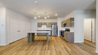This well-designed 3-bedroom, 2-bathroom home offers a thoughtfully laid-out floor plan that balances open communal spaces with comfortable private retreats. The open-concept kitchen serves as the heart of the home, showcasing warm-toned shaker-style cabinetry, granite-look countertops, a subway tile backsplash, and a full suite of stainless steel appliances including a refrigerator, range, microwave, and dishwasher. A central kitchen island provides additional prep and dining space, illuminated by stylish geometric pendant lights overhead. The adjacent living area features durable wood-look luxury vinyl plank flooring, a ceiling fan, and a front entry door flanked by a window that brings in natural light. A carpeted staircase with clean white railings connects to the upper level. The three bedrooms are finished with plush carpet and ceiling fans, offering a comfortable, quiet atmosphere. The primary bedroom includes a walk-in closet with dual hanging rods and built-in shelving. Both bathrooms are finished with wood-look flooring, shaker-style vanities with granite countertops, and tub-shower combos. Three closets throughout the home provide ample storage. The overall aesthetic is clean, modern, and move-in ready.