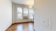 Located in the heart of downtown Milwaukee at 740 N Plankinton Ave, this efficiently designed studio unit makes excellent use of its compact footprint. The open main living area features warm hardwood-style laminate flooring and crisp white walls that create a bright, clean aesthetic throughout. Multiple windows along one wall invite natural light and offer views of the surrounding cityscape, while a wall-mounted HVAC unit ensures year-round climate control. A drum pendant light fixture anchors the living space, adding a modern touch.

The kitchen is thoughtfully appointed with light wood cabinetry, white countertops, and a full suite of stainless steel appliances including a refrigerator, dishwasher, built-in microwave, and an electric cooktop with a single-basin sink — all positioned to maximize efficiency. A large kitchen window provides additional natural light and continued city views.

The bathroom is clean and functional, featuring a full tub and shower combo with a white surround panel system that includes built-in shelving, paired with chrome fixtures. A sliding closet and additional storage are also present within the unit. This streamlined space is ideal for those seeking a practical, well-located residence in Milwaukee's vibrant urban center.