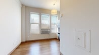 Located in the heart of downtown Milwaukee at 740 N Plankinton Ave, this efficiently designed studio unit makes excellent use of its compact footprint. The open main living area features warm hardwood-style laminate flooring and crisp white walls that create a bright, clean aesthetic throughout. Multiple windows along one wall invite natural light and offer views of the surrounding cityscape, while a wall-mounted HVAC unit ensures year-round climate control. A drum pendant light fixture anchors the living space, adding a modern touch.

The kitchen is thoughtfully appointed with light wood cabinetry, white countertops, and a full suite of stainless steel appliances including a refrigerator, dishwasher, built-in microwave, and an electric cooktop with a single-basin sink — all positioned to maximize efficiency. A large kitchen window provides additional natural light and continued city views.

The bathroom is clean and functional, featuring a full tub and shower combo with a white surround panel system that includes built-in shelving, paired with chrome fixtures. A sliding closet and additional storage are also present within the unit. This streamlined space is ideal for those seeking a practical, well-located residence in Milwaukee's vibrant urban center.