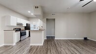 Located at 8120 Mainland Dr in San Antonio, TX 78240, this one-bedroom, one-bathroom residence offers a well-designed single-floor layout that makes efficient use of its space throughout. The interior features wood-look plank flooring in the main living areas, complemented by neutral warm-gray walls and white trim that give the home a clean, modern aesthetic.

The open-concept living and dining area is bright and airy, with a ceiling fan overhead and sliding glass doors that lead directly to a private patio, allowing natural light to fill the space. The kitchen is a functional galley-style layout appointed with white cabinetry, dark granite-style countertops, stainless steel appliances including a dishwasher and refrigerator, and a peninsula with a built-in sink that opens toward the dining area — ideal for casual interaction between rooms. A dedicated laundry area is conveniently accessible from the kitchen.

The bedroom is generously sized, finished with plush carpet, a ceiling fan, a window for natural light, and access to a walk-in closet. The full bathroom features a single-sink vanity with matching dark countertop, white cabinetry, a large mirror, and a shower-tub combination. Multiple additional closets throughout the unit provide ample storage. The private patio rounds out the home with outdoor living space.